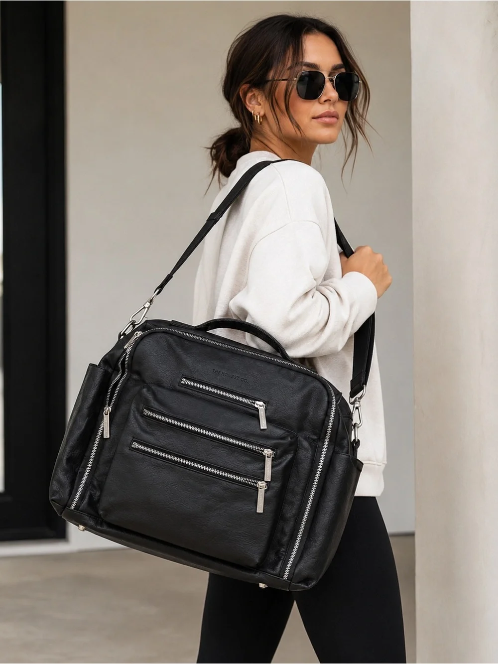 The Honest Company Black Vegan Leather Diaper Bag backpack model cross country